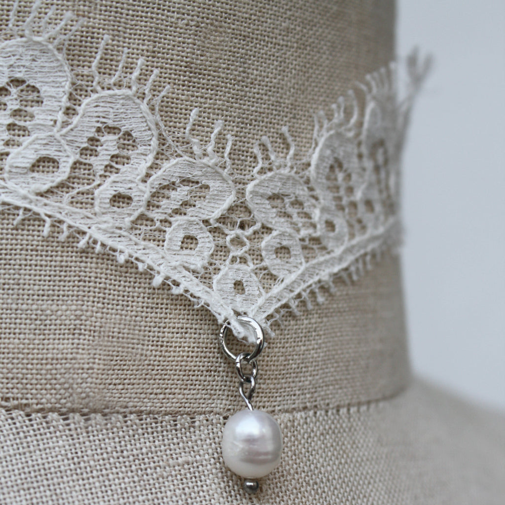 Pearl necklace with lace detail on a mannequin against a neutral background